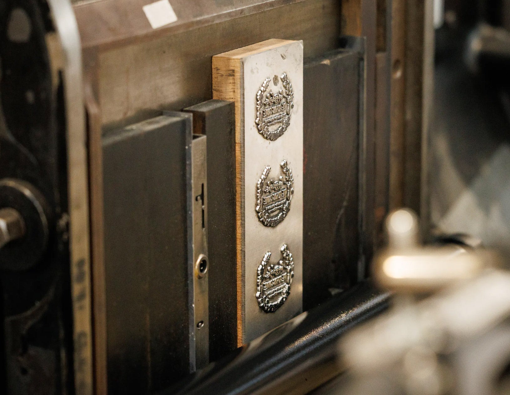 Close-up of a metal stamping machine with engraved designs on a blurred background