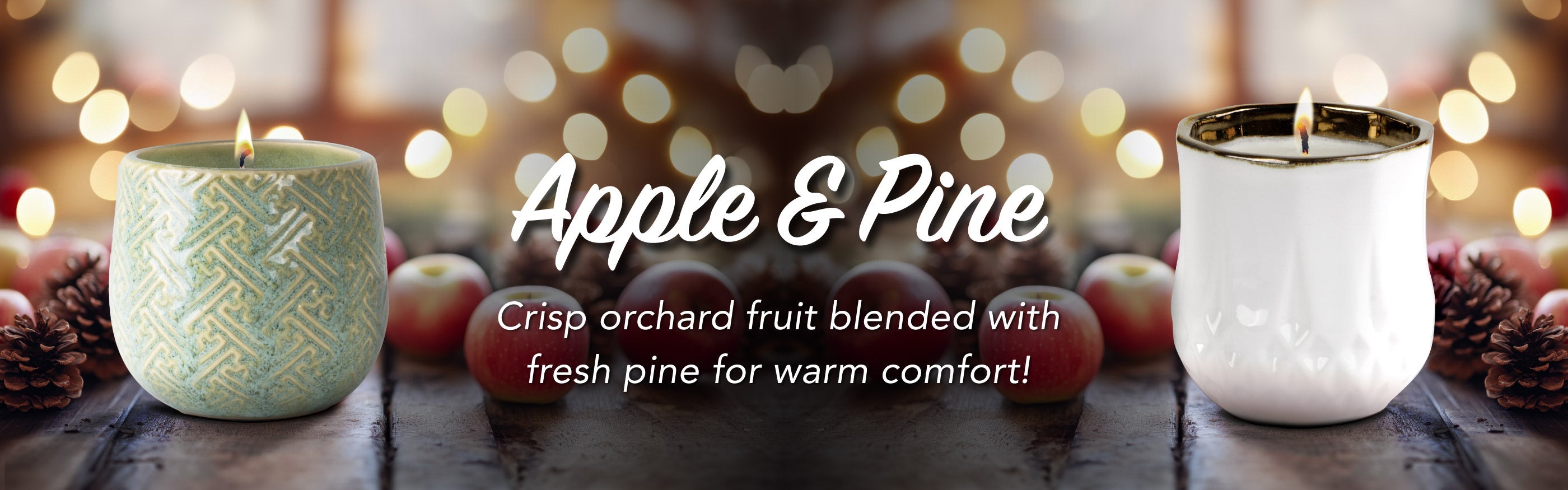 Two candles labeled 'Apple & Pine' on a wooden surface with blurred lights in the background.